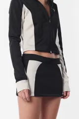 Minifalda deportiva gris con recortes laterales en negro y logo estampado en la parte trasera. Cierre invisible en el lateral.