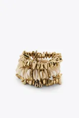 Pack de tres pulseras elásticas con piezas de diferentes formas, tamaños y colores en dorado y blanco.