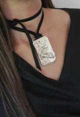 Gargantilla con cinta de cuero negro y dije rectangular de alpaca con textura irregular.