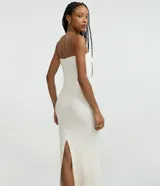 Vestido largo color blanco hueso, de tejido acanalado (rib), corte ajustado al cuerpo y escote recto sin tirantes (strapless).