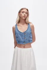 Chaleco crop top de jean celeste con botones frontales.