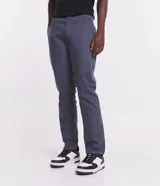 Pantalón de vestir marrón, de corte skinny, con bolsillos laterales y traseros. Se ajusta a la cintura con cinturón de cuero marrón.