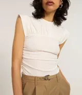 Blusa color crema con cuello redondo y mangas cortas. Presenta un recorte texturizado en el busto y está confeccionada en algodón.