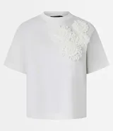 Blusa blanca de algodón con cuello redondo, mangas cortas y apliques de flores de tela en el hombro.