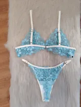 Conjunto de lencería confeccionado en encaje floral color aguamarina con detalles de elásticos en tono champagne. Incluye un corpiño de formato triangular sin aro y una bombacha tipo colaless con breteles regulables.