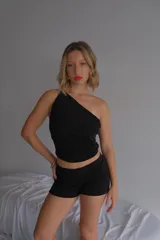 Top negro de manga única (un solo hombro), ajustado al cuerpo, confeccionado en tela de licra/lúrex.