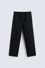 Pantalón negro de corte amplio, con cintura elástica ajustable con cordón, bolsillos laterales y traseros de vivo.