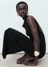 Vestido midi negro de corte ajustado, con cuello barco y espalda descubierta.