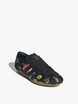 Zapatillas Adidas modelo Tokyo, color negro con bordados florales multicolores. Diseño de corte bajo con las tres tiras laterales y suela de goma color caramelo.