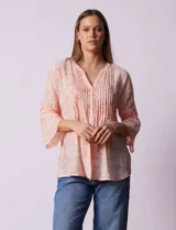 Blusa de gasa estampada color salmón con flores blancas, marca Ruby Rd. Cuello a la base, escote en V y abertura central con botones. Delantera con plisados. Largo de manga ¾ con terminación amplia.