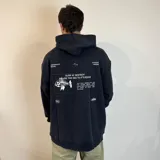 Canguro negro con capucha y corte oversize. Presenta estampados en blanco con motivos marinos y textos alusivos al surf.