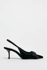 Zapato destalonado de terciopelo negro con tacón fino y adorno de lazo en la parte delantera.