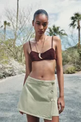 Falda pantalón corta color crudo, de tiro alto con delantero cruzado y cierre con cremallera oculta y botones.
