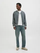 Campera bomber casual color gris verdoso, con cuello tipo baseball y puños de canalé a rayas blancas. Cierre con botones a presión y bolsillos frontales. Confeccionada en tejido liviano y transpirable con hombros caídos.