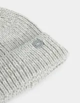 Gorro de lana tejido color rosa viejo, con pompón en la parte superior y etiqueta metálica con logo en el borde.