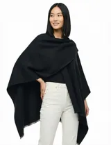 Ruana de tejido soft color beige, con cuello en V y un lazo o pasador frontal para ajustar. El ruedo tiene terminación desflecada.