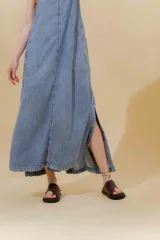Vestido largo de jean celeste con breteles anchos, corte recto, abertura lateral y bolsillo plaqué en el pecho.