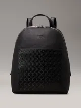 Mochila negra de piel sintética granulada tipo caviar, con bolsillo exterior con textura de logo monograma y logo de metal plateado brillante en la parte delantera. Tiene asa de mano en la parte superior, correa para el hombro ajustable, cierre de cremallera en la parte superior con logo brillante en los tiradores y bolsillos interiores con ranura.