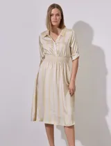 Vestido midi camisero de satén estampado a rayas verticales amarillas y beige. Tiene cuello con solapa, escote en V, abertura con botones, cintura elastizada y mangas cortas regulables con presilla y botón.