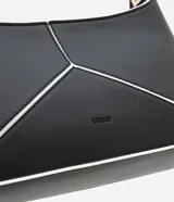 Cartera baguette mediana de cuero sintético color negro, con recortes geométricos en blanco en el frente y asa corta con detalle metálico.