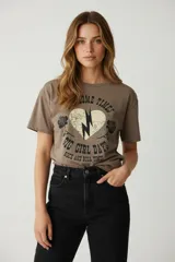 Remera de algodón color marrón topo, corte holgado, con cuello redondo a la base y estampado frontal con un corazón con un rayo y rosas, y texto que dice "SOME TIMES BIG GIRL DAYS ROCK AND ROLL TIMES".