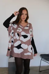 Poncho de tejido de punto color marrón con estampado animal print en blanco y negro, con cuello en V y mangas cortas.