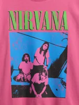 Remera rosa con estampado de la banda Nirvana y logo en verde y celeste.