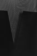 Body negro de cuello redondo y sin mangas, con parte superior de tul transparente y cierre inferior con broches a presión.