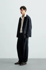 Blazer azul oscuro de denim, corte relaxed fit, con cuello de solapas de muesca, manga larga con puños abotonados, bolsillos de solapa en la cadera, abertura en el centro de la espalda y cierre frontal con botones.