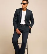 Pantalón de traje de corte super slim, color azul oscuro, confeccionado en tejido de poliviscosa con textura discreta. Presenta trabillas en la cintura, cierre de cremallera y botón, y bolsillos laterales y traseros.