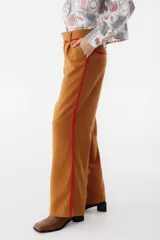 Pantalón de vestir color marrón con corte recto y cintura alta. Presenta una fina cinta roja a modo de cinturón.