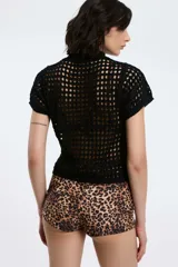 Top negro calado de tejido de punto con cuello alto y mangas cortas.