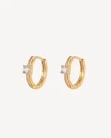 Aros tipo argolla dorados con un pequeño cristal blanco.