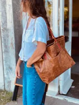 Bolso tote de cuero color marrón con asas trenzadas en marrón y rojo.