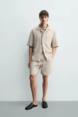 Bermuda negra de lino con calce relajado. Presenta cintura elástica ajustable con cordón, bolsillos frontales y un bolsillo trasero de plastrón.