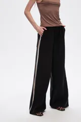 Pantalón negro ancho de viscosa con vivos laterales en blanco, dorado y marrón.