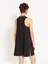 Vestido corto negro de poplín con cuello redondo y sin mangas. Presenta apliques de piedras negras en la parte delantera y trasera.