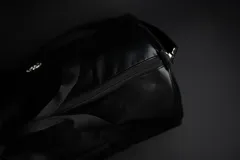 Bolso duffel negro de cuero sintético con logo de ancla bordado en rosa. Tiene doble asa de mano reforzada, correa de hombro regulable y desmontable, cierre superior con doble cremallera y tres bolsillos (dos exteriores y uno interior).