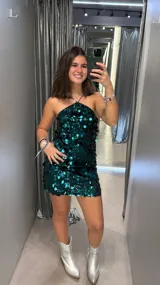 Vestido corto de lentejuelas color verde esmeralda, con escote halter y espalda descubierta.