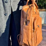 Mochila de cuero color marrón claro con múltiples bolsillos y cierres.