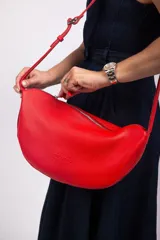 Bandolera de cuero graneado color marrón, con correa ajustable y forma de media luna.
