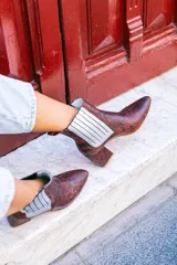 Botín de cuero con estampado de piel de serpiente en tonos marrón y rojo, con elásticos laterales plateados y tacón cuadrado.