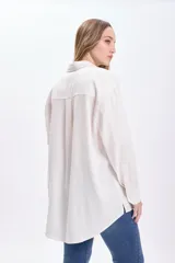 Camisa blanca de lino de manga larga con cuello clásico, cierre frontal con botones y bolsillo en el pecho.