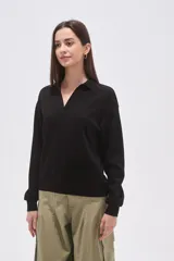 Buzo negro de manga larga con cuello polo y escote en V. Tiene un corte holgado y puños y dobladillo acanalados.