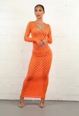 Vestido midi naranja de tejido calado con aberturas circulares, escote cuadrado y mangas largas ajustadas.