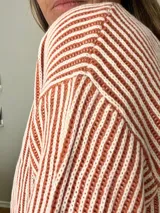 Suéter tejido de corte relajado con diseño a rayas finas en color crudo y verde militar. Tejido suave y abrigado con cuello redondo clásico.