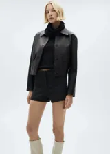 Top negro de tejido de punto fino, cuello alto y diseño entallado sin mangas.