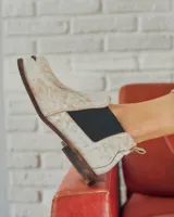 Botines Chelsea de cuero negro con elástico lateral y suela marrón.