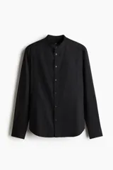 Camisa negra de corte estándar, con cuello mao, tapeta clásica y mangas largas con puños abotonados.
