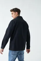 Sobrecamisa verde militar de algodón grueso tipo canvas, con cuello clásico, cierre frontal con botones, dos bolsillos de parche en el pecho con solapa abotonada y dos bolsillos de parche en la parte inferior.